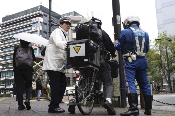 Các cảnh sát giải thích hệ thống phạt tại chỗ "vé xanh" cho một người đi xe đạp trên đường phố ở quận Kita, Tokyo. Ảnh: The Yomiuri Shimbun