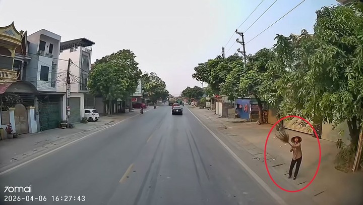 Người phụ nữ bên đường giơ chiếc chổi lên ra hiệu thì xe tải mới dừng lại.