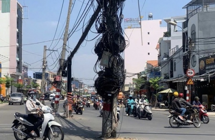 Dây cáp trên trụ điện sà xuống đường khiến nhiều người di chuyển ái ngại sợ bị vướng vào nếu không chú ý.