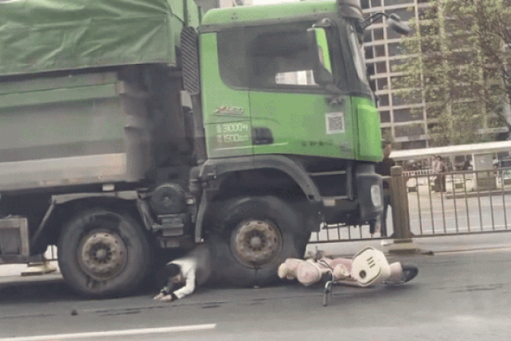 Người phụ nữ đi xe máy chui ra từ gầm xe ben