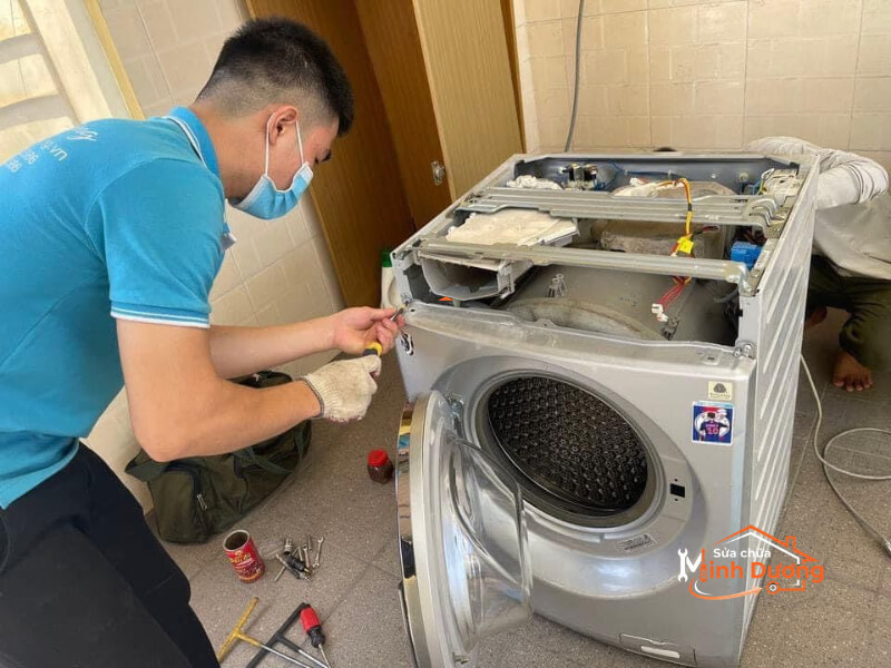 Kỹ thuật viên tay nghề cao của Minh Dương Fix đang cẩn thận tháo dỡ và đo đạc hệ thống bo mạch máy giặt Inverter tại nhà khách hàng, cam kết bắt đúng bệnh, không vẽ lỗi.