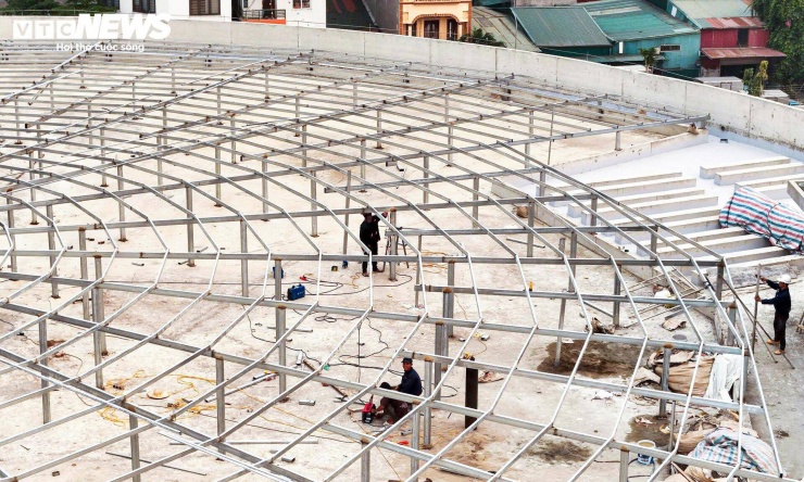 Trên công trường, nhiều công nhân tập trung lắp dựng hệ khung thép trên mái, chuẩn bị cho các hạng mục hoàn thiện tiếp theo.