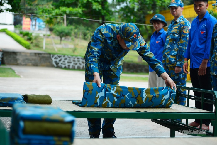 Chiến sĩ hướng dẫn học sinh từng thao tác cơ bản để gấp chăn đúng nếp.