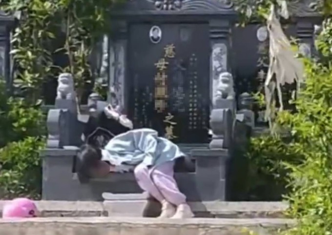Cô bé đòi xin nằm ngủ ngay cạnh mộ của ông bà. Ảnh: Weibo