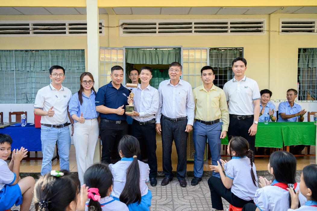 Cúp Quán quân “Maxilite - Rulô Vàng” được trao tặng cho anh Nguyễn Văn Minh Kha (đứng chính giữa) ngay tại Lễ bàn giao điểm trường Tiểu học Nhơn Ái