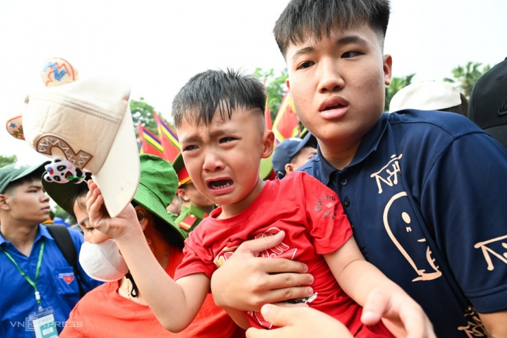 Một em bé bật khóc khi được người thân đưa ra khỏi đám đông.