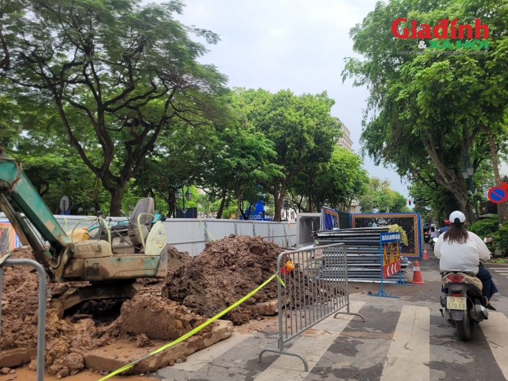 Công nhân vận hành máy xúc, lắp đặt cấu kiện bê tông trong điều kiện mặt bằng chật hẹp, giao thông vẫn phải duy trì hai bên. Phần đường còn lại được thu hẹp chỉ còn khoảng 3 - 4m mỗi bên, đủ cho các phương tiện di chuyển chậm, nhích từng nhịp qua khu vực thi công.