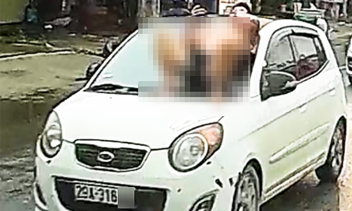 Người đàn ông nằm trên nắp capo ô tô đang chạy.