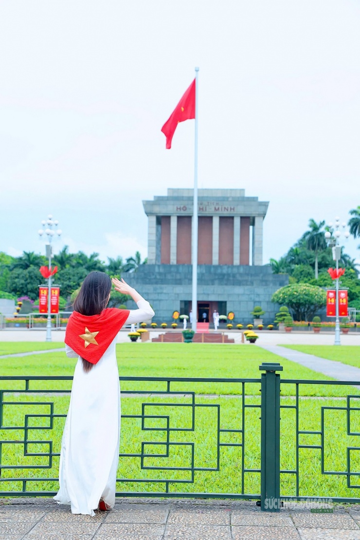 Tà áo dài trắng và lá cờ Tổ quốc tạo nên khung hình trang trọng trước Lăng Chủ tịch Hồ Chí Minh.