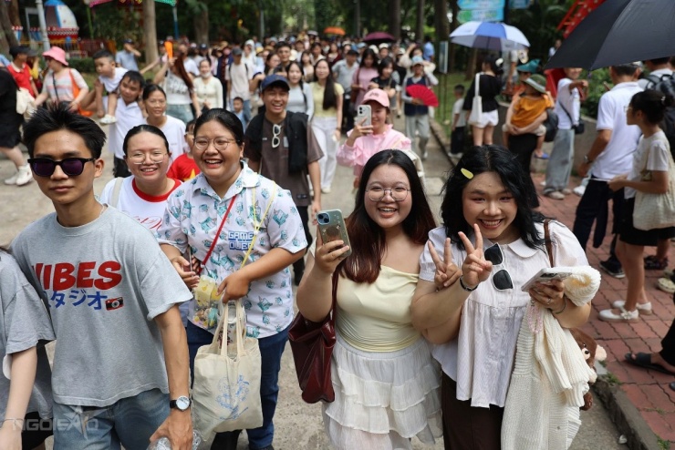Dọc hai bên lối đi, du khách liên tục giơ điện thoại ghi hình. Một số người tranh thủ tiến lại gần để chụp ảnh khi đoàn đi ngang.