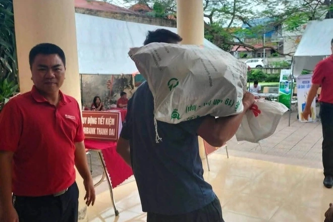 Người dân làm thủ tục tại nhà văn hóa, mang bao tải đựng tiền đền bù đất. Ảnh: UBND xã Thanh Oai