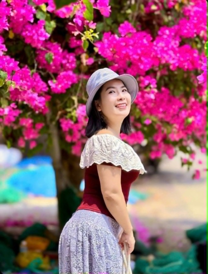 Ái Vân tạo dáng dưới tán cây hoa giấy. Ảnh: NVCC