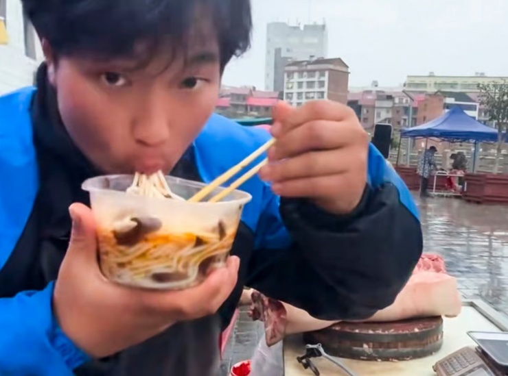 Sun Pan tranh thủ ăn khi đi bán hàng. Ảnh: SCMP