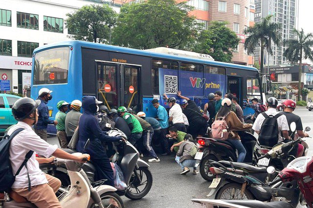 Người dân cùng lực lượng chức năng nâng xe buýt giải cứu người phụ nữ mắc kẹt. Ảnh: NDCC