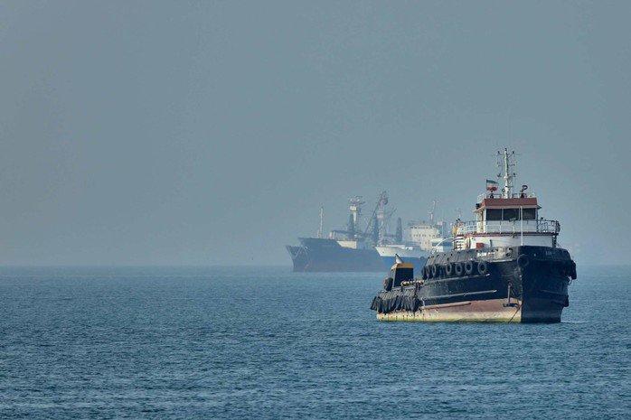 Một tàu kéo Iran ở phía trước, trong khi các tàu chở hàng đang neo đậu tại eo biển Hormuz ngoài khơi Bandar Abbas - Iran ngày 4-5. Ảnh: AP