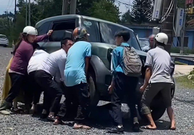 Nhiều người hợp sức khiêng ôtô cứu nạn nhân mắc kẹt dưới gầm. Ảnh: Hoài Thanh