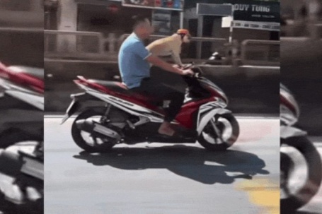 Người đầu trần chạy xe máy chở chó đội mũ bảo hiểm trên quốc lộ gây xôn xao