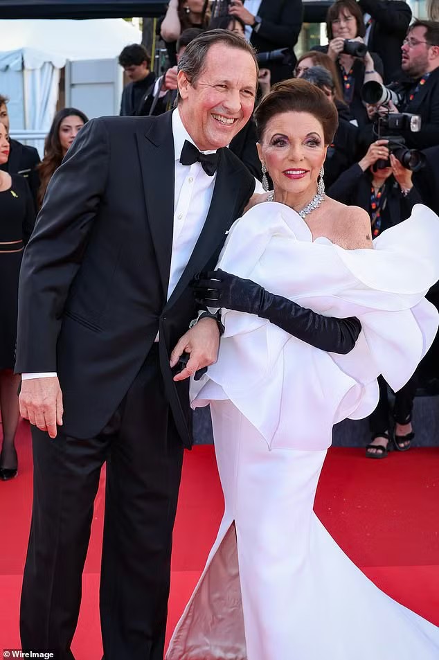 Nữ diễn viên gạo cội Joan Collins quyến rũ trong chiếc váy trắng, kết hợp cùng vòng cổ kim cương và găng tay đen. Đối với bà, tuổi 93 dường như chỉ là con số. Sánh đôi cùng Collins là chồng Percy Gibson (61 tuổi). Ảnh: WireImage/Shutterstock
