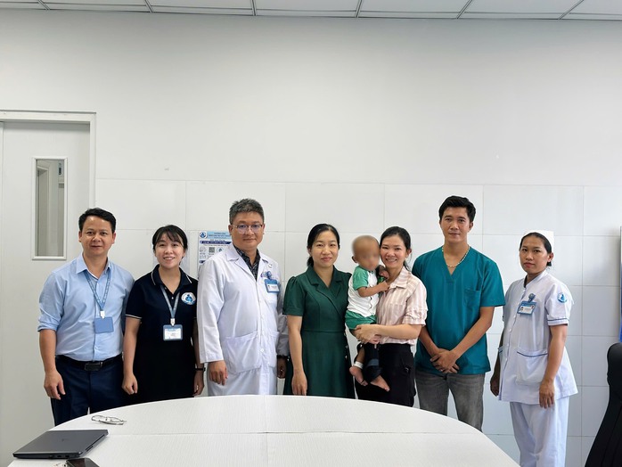 Bác sĩ, nhân viên Bệnh viện Nhi Đồng 1 chụp hình lưu niệm cùng bé trai trước khi xuất viện