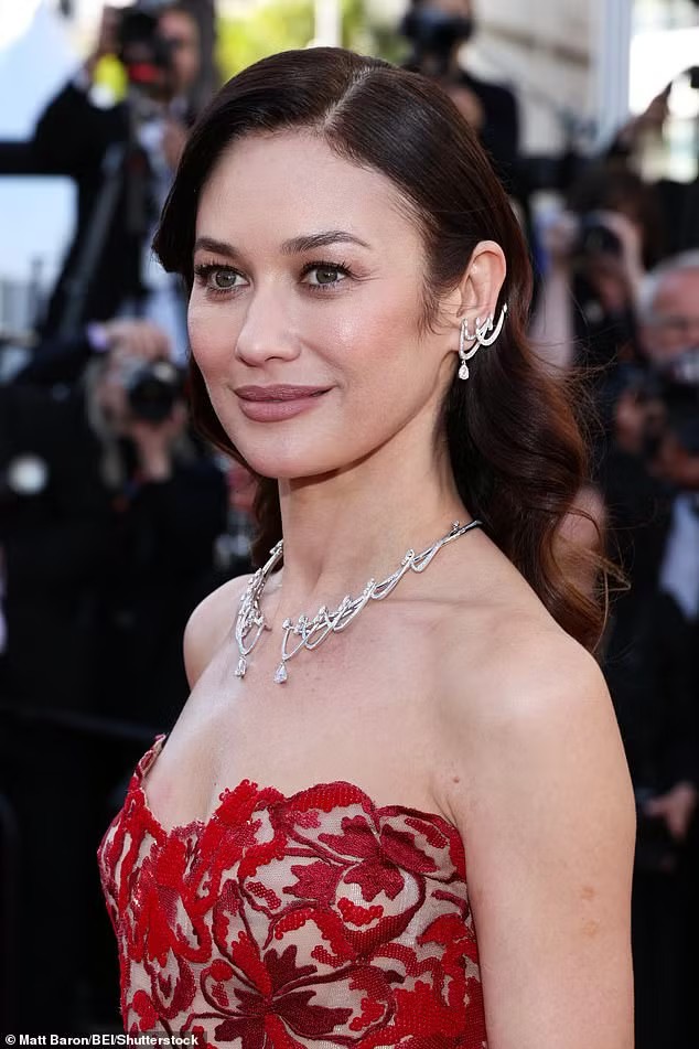 "Bond girl" Olga Kurylenko đằm thắm ở tuổi 46. Cô mặc váy dạ hội màu đỏ xuyên thấu theo phong cách baroque (trào lưu nghệ thuật và kiến trúc bắt nguồn từ Italy vào năm 1600, nổi bật với các đường nét uốn lượn), kết hợp cùng phụ kiện và ví cầm tay của Roger Vivier. Ảnh: Shutterstock/Getty Images