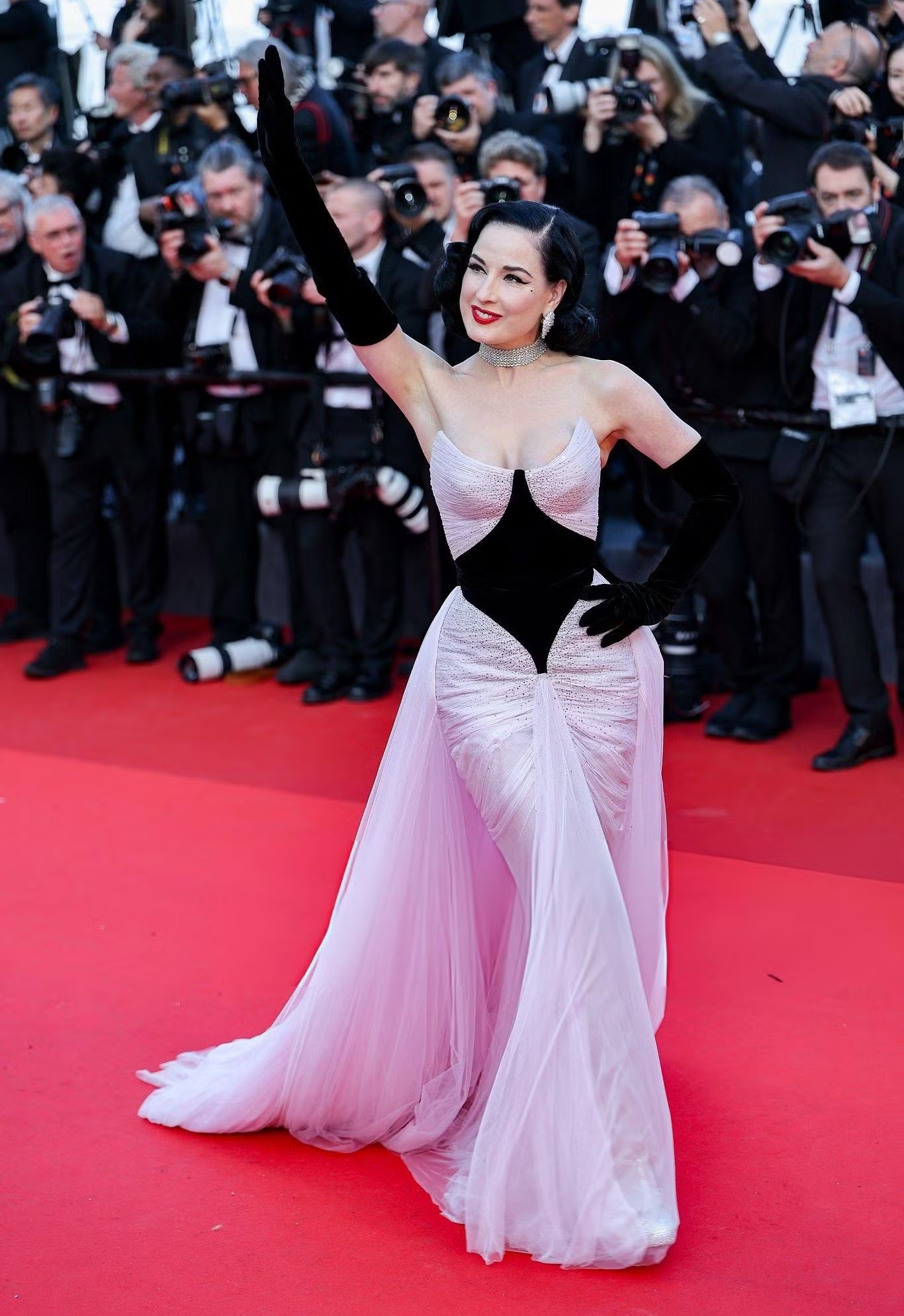 Vũ nữ thoát y Dita Von Teese xuất hiện trong thiết kế hồng pastel của Tamara Ralph với lớp tulles, chi tiết nhung đen và đường cắt cổ áo vintage. Trang sức Chopard cùng son đỏ hoàn thiện tổng thể cổ điển quyến rũ.