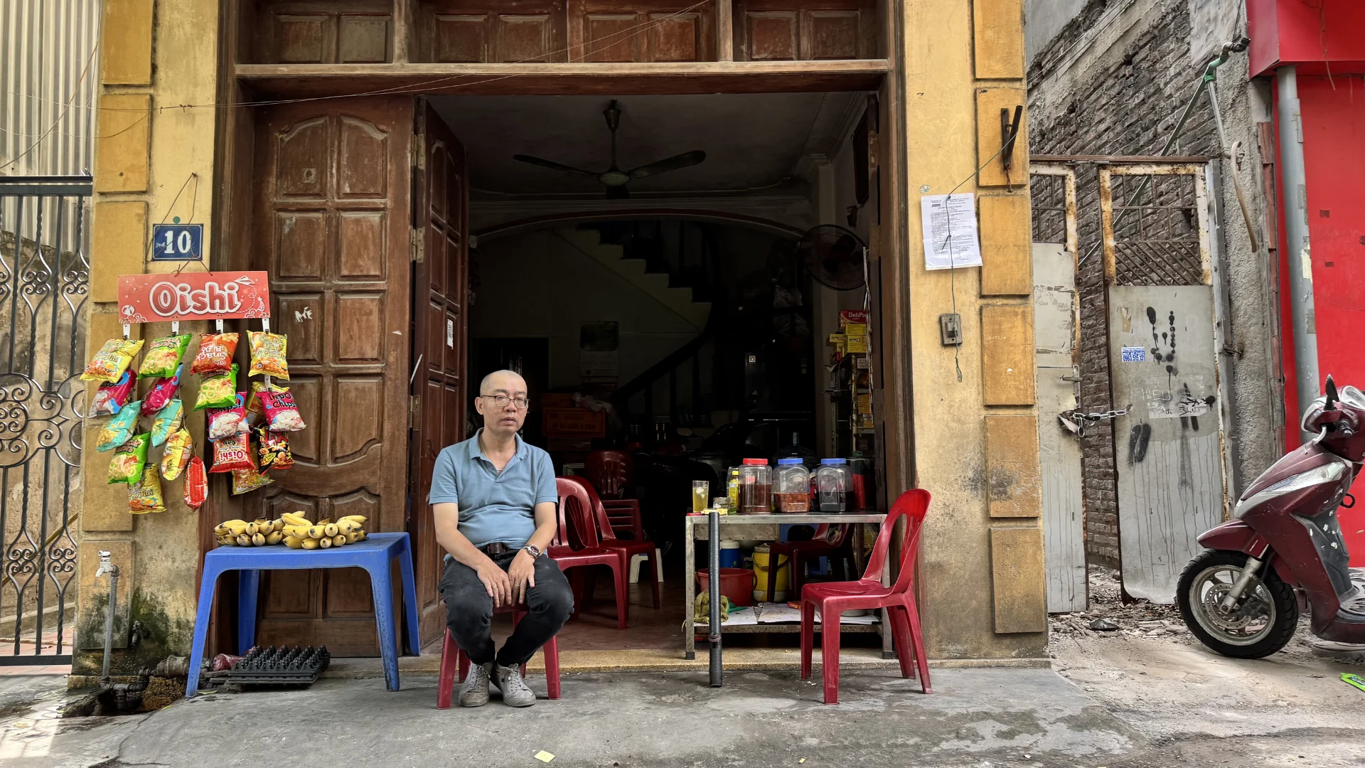 Ông Hà ngồi trước căn nhà đã gắn bó nhiều năm tại phường Bồ Đề, nơi gia đình ông có thể phải di dời để phục vụ dự án Trục đại lộ cảnh quan sông Hồng. Ảnh: Anh Văn