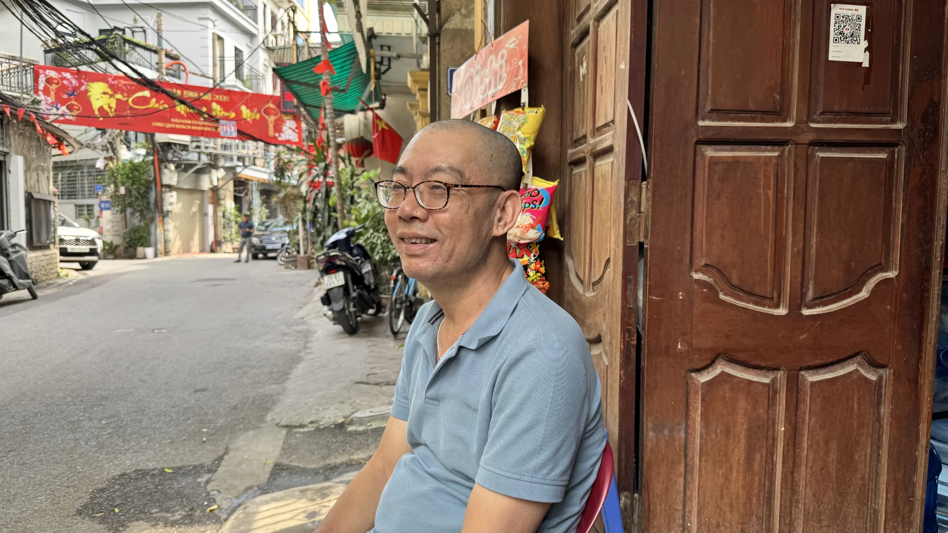 Ông Hà ngồi trước căn nhà đã gắn bó nhiều năm tại phường Bồ Đề, nơi gia đình ông có thể phải di dời để phục vụ dự án Trục đại lộ cảnh quan sông Hồng. Ảnh: Anh Văn