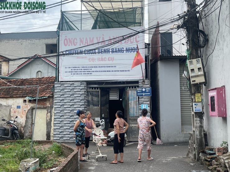Người dân trong xóm trước cổng cơ sở chữa bệnh bằng nước sau khi ông Nguyễn Tiến Nam bị bắt.