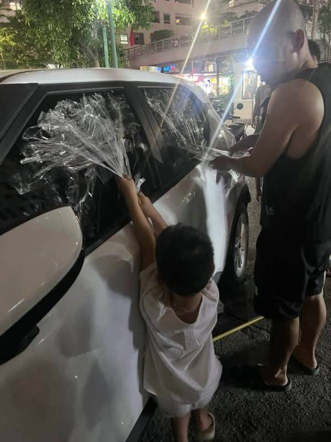 Người dân sử dụng băng dính để mở cửa giải cứu em bé bên trong ô tô . Ảnh: Cộng đồng cư dân HH Linh Đàm