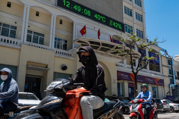  Biển hiển thị trên đường Láng Hạ ghi nhận mức nhiệt 40 độ  C lúc 12h ngày 25/5. Đường phố vắng vẻ, người có việc cần kíp phải ra đường đều trùm kín mít. Ảnh:Thế Bằng  