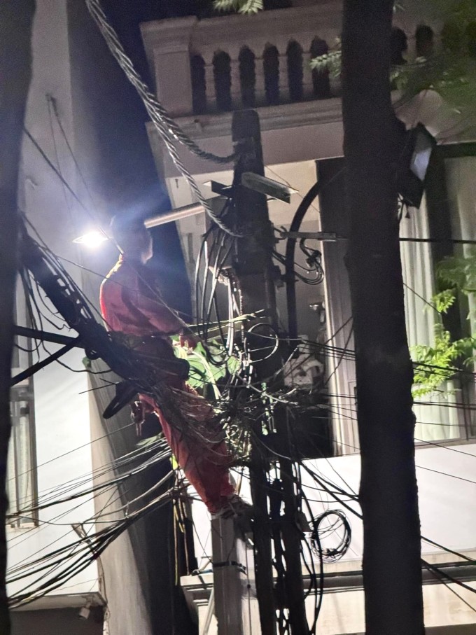 Một nhân viên điện lực khắc phục đường điện sau khi nhận phản ánh của người dân trên phố Triều Khúc, phường Thanh Xuân đêm muộn 25/5. Ảnh: Pham Van Hai