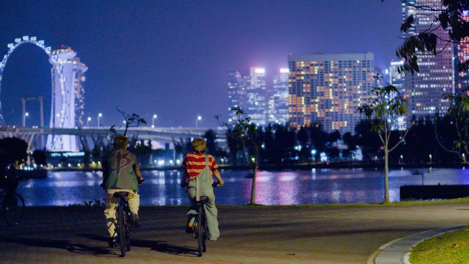 Hai nghệ sĩ thử đạp xe đêm quanh khu Marina Bay để trải nghiệm nhịp sống đô thị. Ảnh: NVCC