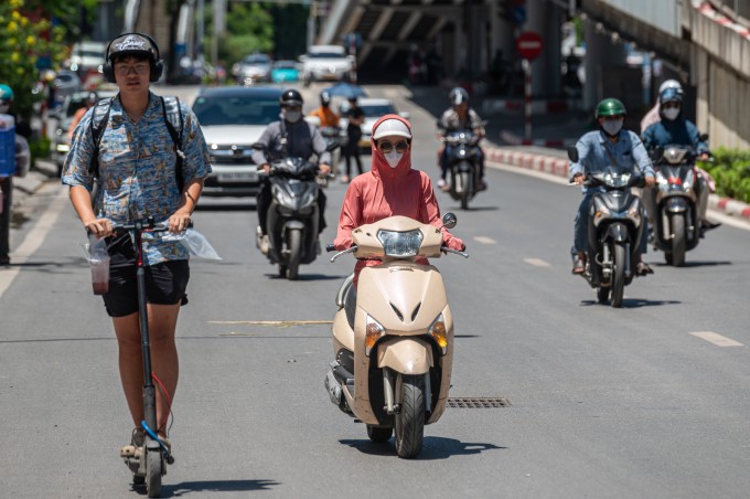 Người dân trùm kín để bảo vệ cơ thể khi di chuyển ngoài đường trong đợt nắng nóng cao điểm tại Hà Nội, ngày 26/5. Ảnh: Thế Bằng