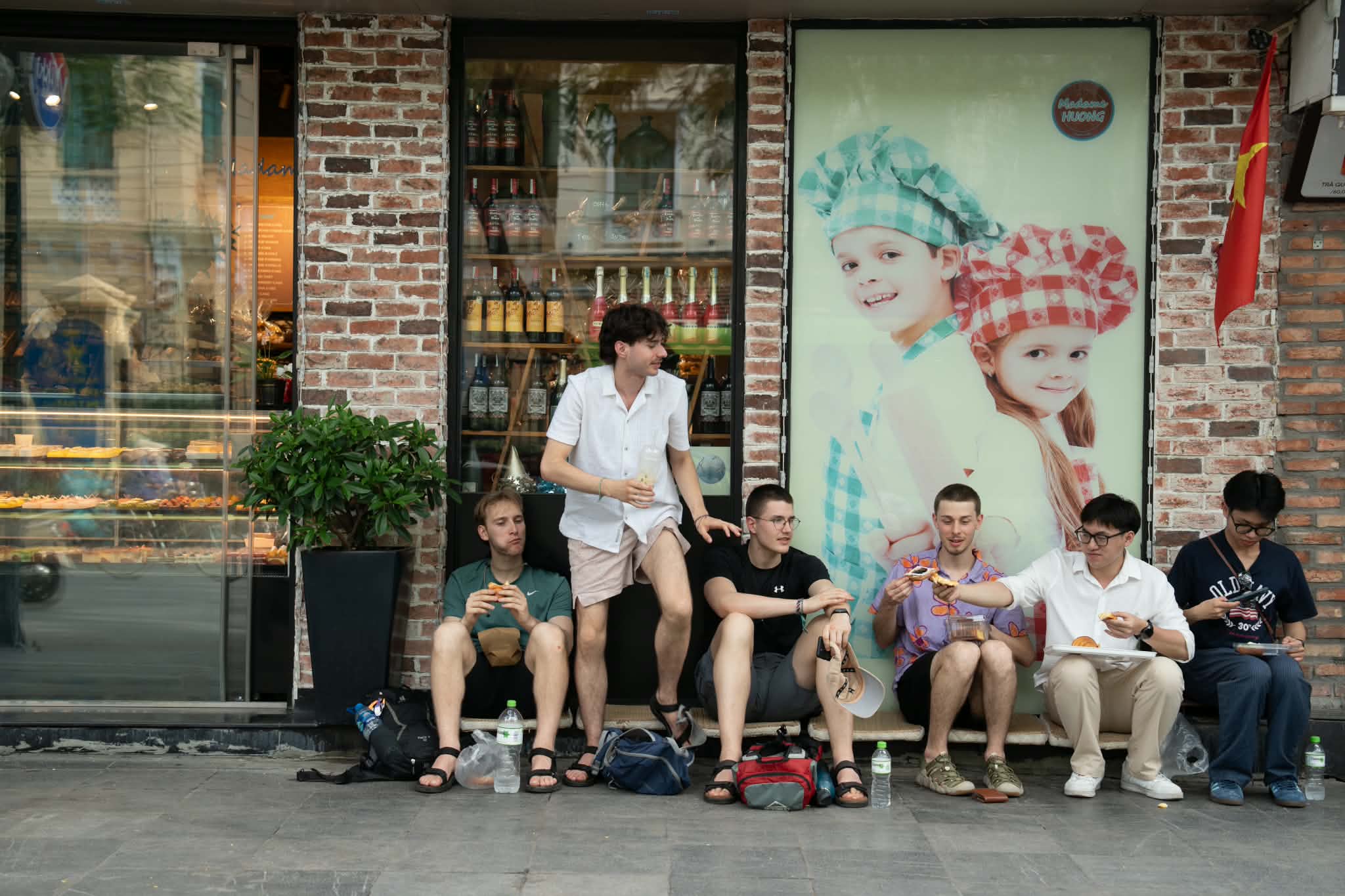 Khách du lịch ngồi nép sát vào vỉa hè trên phố Lý Thường Kiệt, phường Hoàn Kiếm, Hà Nội, ăn bánh mì chiều 13/5.