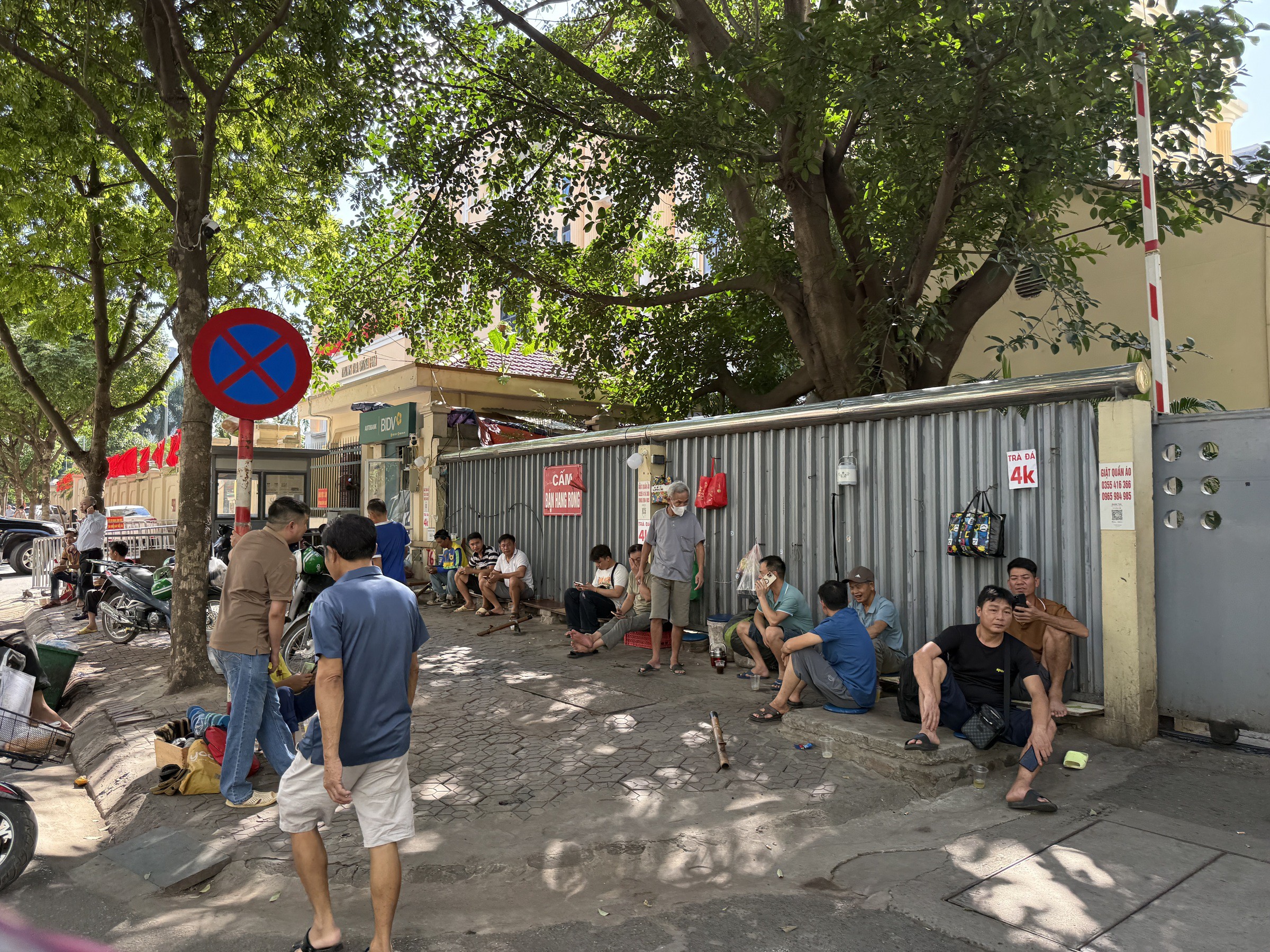 Người dân ngồi uống trà đá tại cổng sau Viện Huyết học - Truyền máu Trung ương nhưng không thấy người bán hàng.