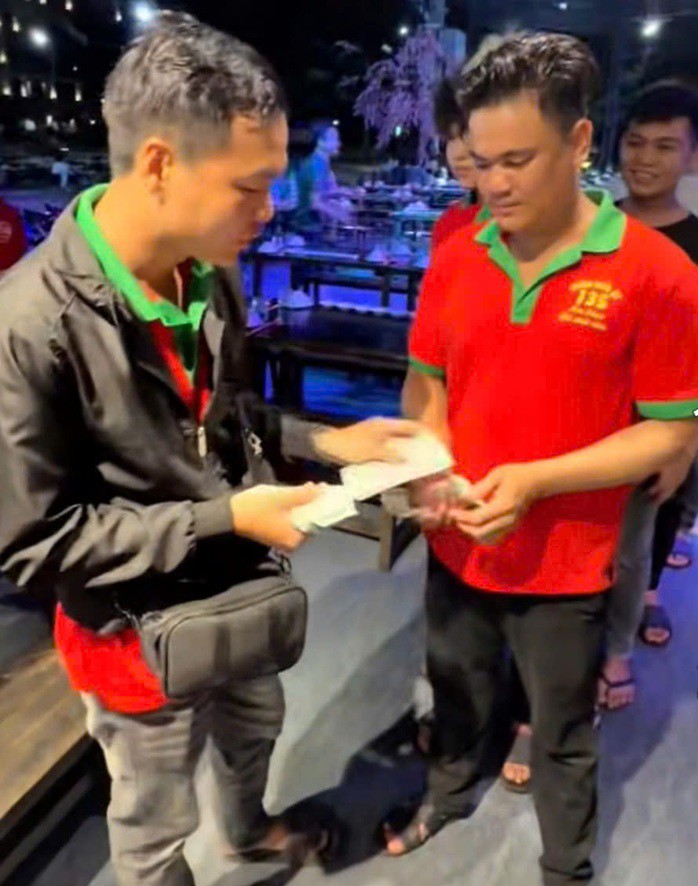 Anh Phát (trái) tặng tiền cho nhiều đồng nghiệp sau khi trúng độc đắc 18 tỉ đồng. Ảnh cắt ra từ clip