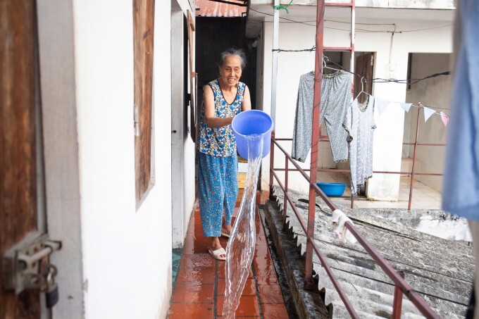 Bà Vũ Thị Quy dội nước làm mát tại hành lang tầng hai của căn trọ ở thôn Hậu Dưỡng, xã Thiên Lộc, chiều 3/6. Ảnh: Nga Thanh
