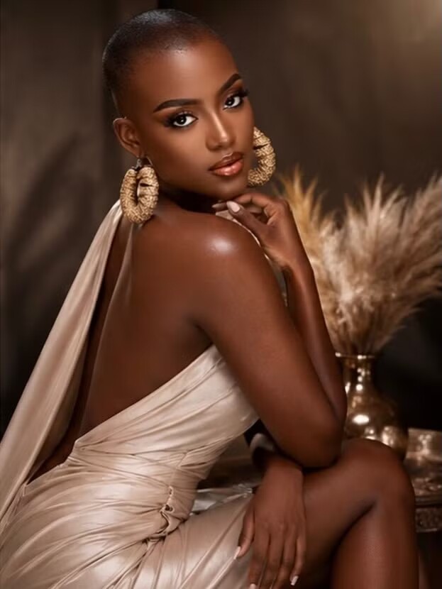 Rebecca Attiogbe 23 tuổi, cao 1,78 m, gây ấn tượng với đầu trọc và vẻ ngoài mạnh mẽ, cá tính. Rebecca Attiogbe là á hậu 1 tại Miss Grand Ghana 2025. Tại Miss Grand Ghana 2025, người đẹp Maria Faith Porter giành chiến thắng và đại diện Ghana tham dự Hoa hậu Hòa bình Quốc tế 2025, giành giải á hậu 3. Mới đây, Maria Faith Porter tiếp tục dự thi MGI All Stars 2026 và giành giải á hậu 1.