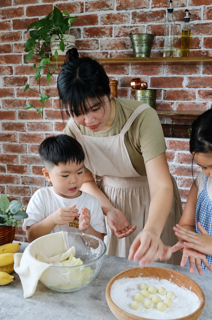 Chị Hoa hướng dẫn hai con làm món chè chuối. Ảnh: NVCC