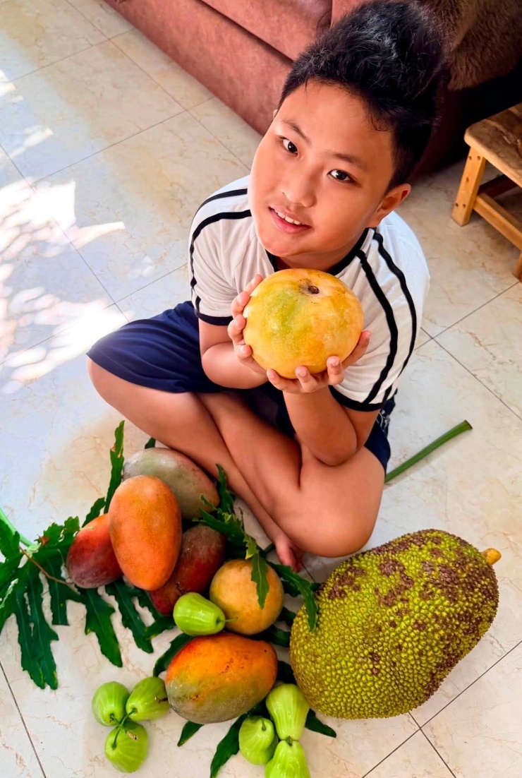 Con trai Mỹ Lệ bên những loại trái cây vừa thu hoạch. Ảnh: FBNV