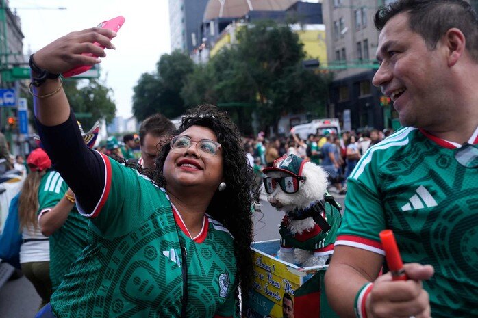 CĐV thích thú chụp ảnh cùng Osito trước trận Mexico - Hàn Quốc ở bảng A World Cup 2026 tại Mexico City hôm 19-6 (giờ Hà Nội). Chú chó 8 tuổi mặc áo tuyển Mexico, đeo kính và ngồi sau xe của chủ nhân Jorge Rangel. Ảnh: AP
