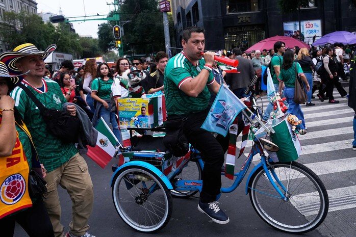 Ông Jorge Rangel chở Osito trên chiếc xe đạp được trang với cờ Mexico, hòa vào dòng CĐV trước trận đấu của đội chủ nhà gặp Hàn Quốc ở lượt trận thứ 2 bảng A. Người đàn ông 50 tuổi xem Osito là bạn đồng hành hằng ngày. Ảnh: AP