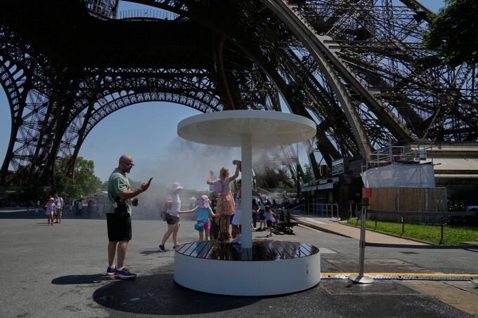 Người dân giải nhiệt bên cạnh vòi phun nước gần tháp Eiffel ở Paris ngày 21/6. Ảnh: AP