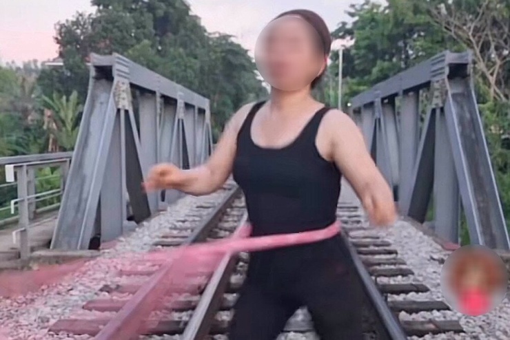 Người phụ nữ đứng tập lắc vòng trên đường ray tàu hỏa. Ảnh chụp màn hình
