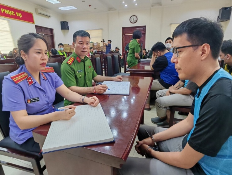 Trần Đạo Tú (đeo kính áo xanh) tại cơ quan công an.
