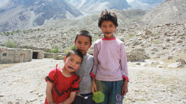Những đứa trẻ đứng cạnh một ngôi nhà đá của người Kyrgyzstan dọc tuyến đường Karakoram.