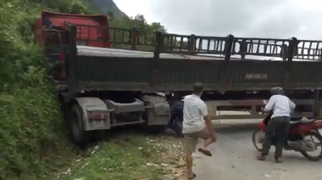 Xe chở cột điện chắn ngang quốc lộ, dân chui gầm xe qua đường - 1