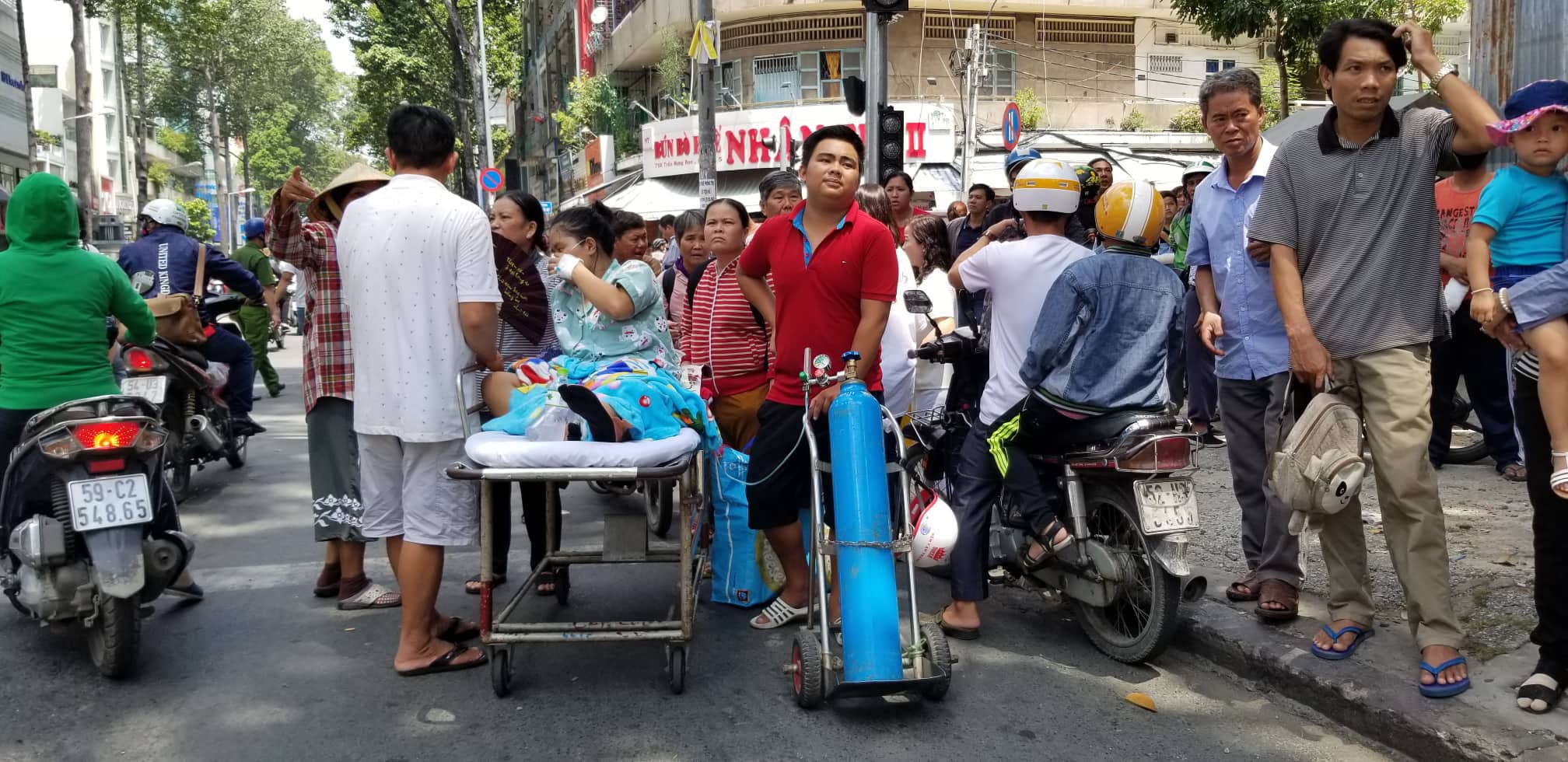 Nhiều bệnh nhân nằm trên băng ca được di tản ra đường kèm theo bình oxy