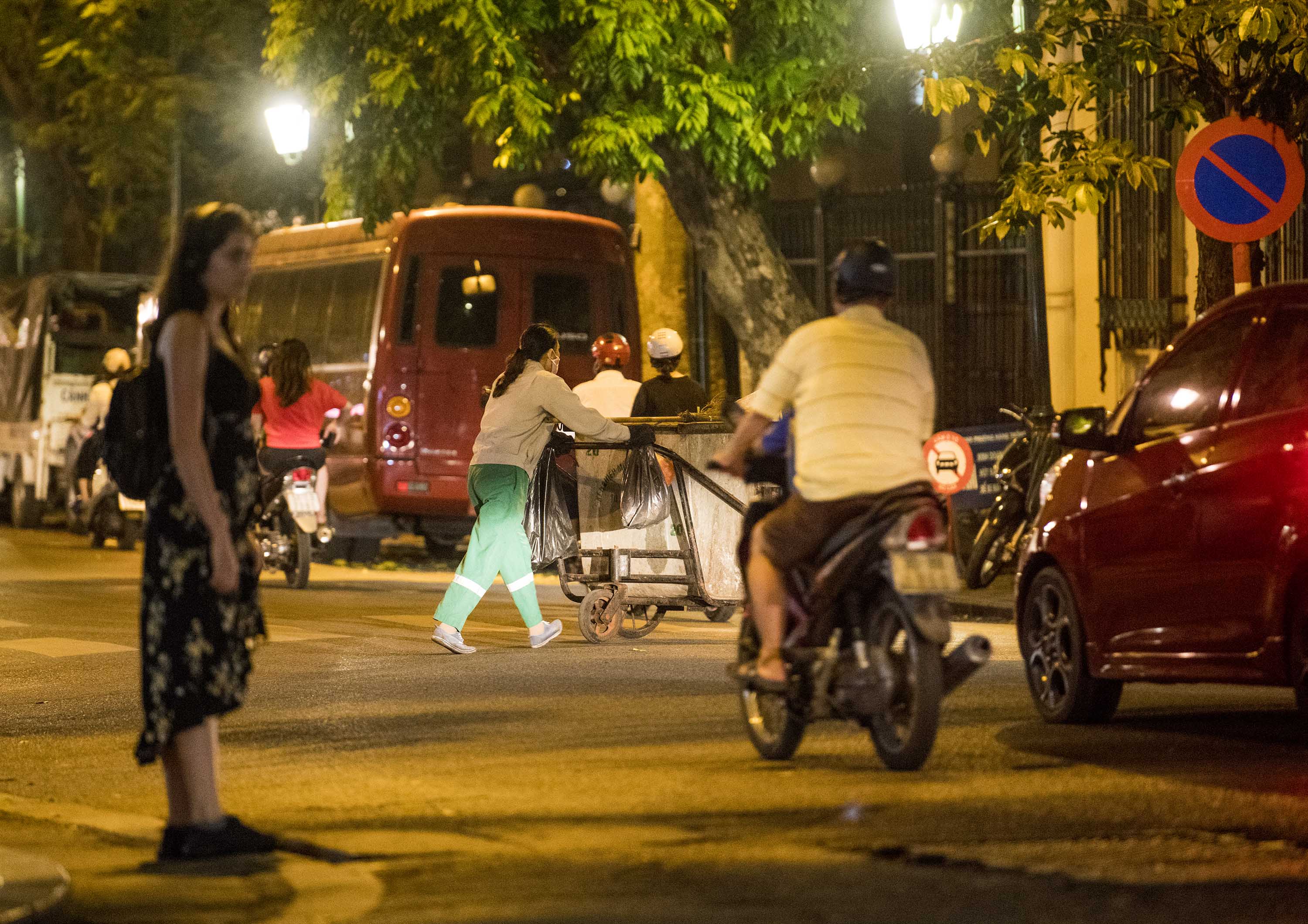 Làm việc buổi tối, trên đường có nhiều phương tiện giao thông nhưng một số công nhân môi trường không đội mũ bảo hộ, không mang áo phản quang.