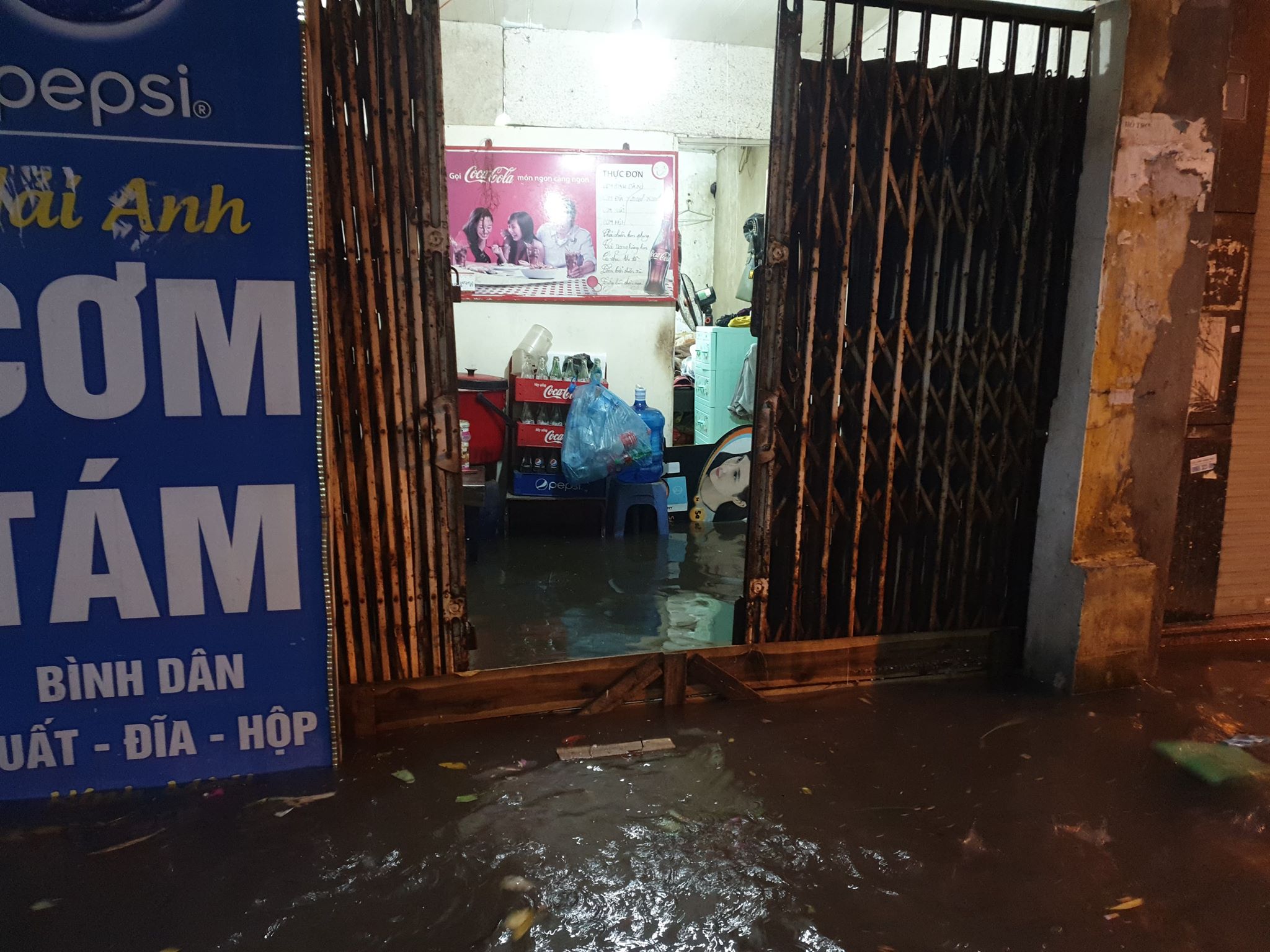 Nước ngập sâu tràn vào nhà, một số người dân phải dùng tấm gỗ để chắn trước cửa để ngăn sóng và rác trôi vào nhà.